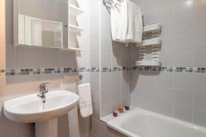 a white bathroom with a sink and a toilet at Flatguest La Herradura in Telde