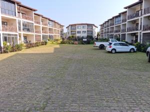 un aparcamiento con coches estacionados frente a los complejos de apartamentos en 24 Topanga, en Uvongo Beach