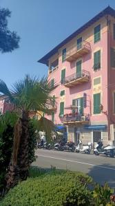 a palm tree in front of a pink building at Hotel Serena in Arenzano