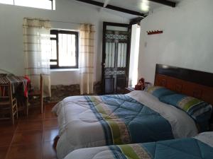 a bedroom with two beds and a table and a window at casa montañista lodge & camping in Huaraz