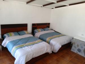 two beds in a room with white walls at casa montañista lodge & camping in Huaraz