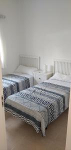 Duas camas num quarto com paredes brancas em La Casita del pescador em Cabo de Palos