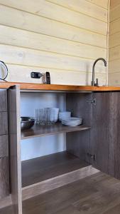 a kitchen with a sink and plates on a shelf at Гостинично-банный комплекс PARADISE in Shchūchīnsk