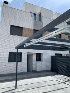 a white brick building with a black garage at Acogedora casa en Madrid con piscina privada, jacuzzy y garaje in Madrid