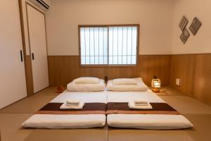 two beds in a large room with a window at Irodori Hotel AI in Fukuoka