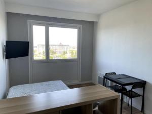 a room with a bed and a desk and a window at Studio Horizon Bleu, vue mer in Calais