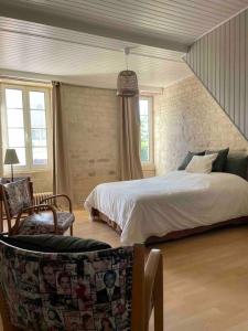 una camera con letto, sedia e finestre di Maison typique en pierre de Caen - 4 voyageurs a Louvigny