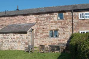 a brick building with a table and chairs in front of it at The Shippon Barn - A delightful haven for families in Wirral