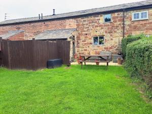a picnic table in a yard next to a brick building at The Shippon Barn - A delightful haven for families in Wirral