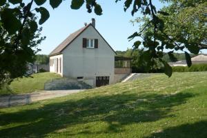 una casa blanca en una colina con un campo verde en Gite de la Vallée de Mai, 