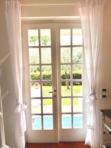 eine offene Tür mit weißen Vorhängen in einem Zimmer in der Unterkunft Canevon Suite Apartment in Bardolino