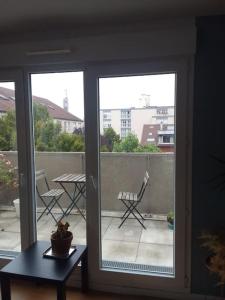 een glazen schuifdeur met een tafel en stoelen op een balkon bij Chambre pour deux personnes dans un logement partagé Two persons room in a shared apartment in Alfortville