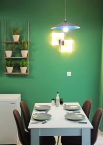 uma sala de jantar com uma mesa com cadeiras e uma parede verde em Sky Nomads em Tessalônica