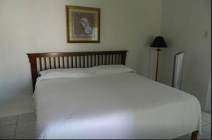 a white bed in a bedroom with a picture on the wall at Jamrock Secret Retreat in Montego Bay