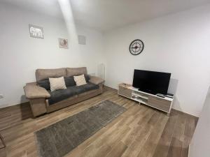 uma sala de estar com um sofá e uma televisão de ecrã plano em Loft Fontanales em Agua de Fontanales