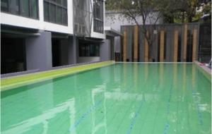 an empty swimming pool with green water in a building at Vinn condo in Amphoe Phra Khanong