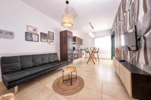 a living room with a black couch and a tv at Casa Costa Esmeralda Plus-Pool and Relax in Costa Teguise