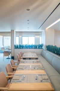 une grande salle à manger avec de longues tables et chaises dans l'établissement SENSEANA Sea Side Resort & Aquadventure, à Chersónissos