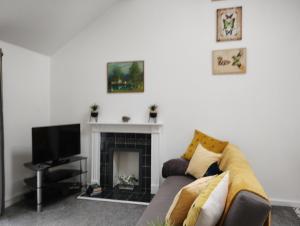 a living room with a couch and a fireplace at Cwtch Cottage in Rhondda