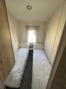 two beds in a small room with a window at Butlins Skegness Caravan in Lincolnshire