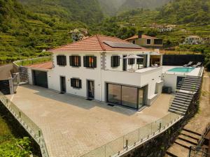 a large white house with a swimming pool and mountains at Casa Avô da Pedra, By OP in São Vicente