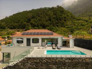 a house with a swimming pool in front of a mountain at Casa Avô da Pedra, By OP in São Vicente