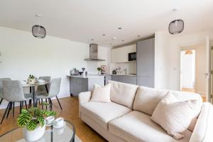 a living room with a white couch and a kitchen at Epsom Modern Luxury 1 Bed Apartment with Extra Sofa Bed - East Street in Epsom