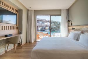 een slaapkamer met een bed, een bureau en een raam bij SENSEANA Sea Side Resort & Aquadventure in Chersonissos