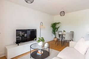 a living room with a white couch and a tv at Epsom Modern Luxury 1 Bed Apartment with Extra Sofa Bed - East Street in Epsom