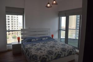 a bedroom with a bed with a floral comforter and windows at 1BR apartment, Stunning Dubai Marina view, 5 min walk to JBR beach, 30 sec walk to tram and bus stations in Dubai