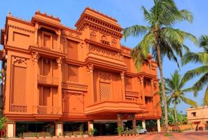 an orange building with a palm tree in front of it at Haveli Backwater Resort in Alleppey