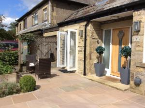 a patio with two chairs and a house at Hardy Croft Hideaway in Grassington