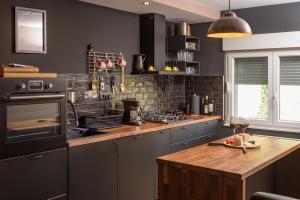 uma cozinha com armários cinzentos e um balcão de madeira em Chill House Keti 