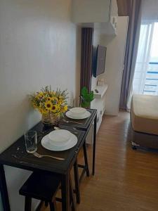 a table in a room with two plates and flowers on it at Studio with Balcony at The Loop Tower in Cagayan de Oro