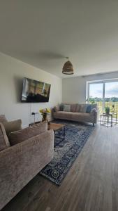 a living room with two couches and a large window at The Oasis, SAV - Romney Sands Beach House in Littlestone-on-Sea