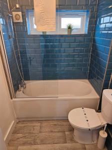 a bathroom with a tub and a toilet at Tudors eSuites Cosy Two Bedroom Apartment with 6 Beds in Birmingham