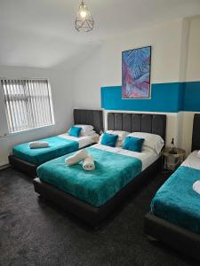 trzy łóżka w pokoju niebiesko-białym w obiekcie Tudors eSuites Cosy Two Bedroom Apartment with 6 Beds w Birmingham