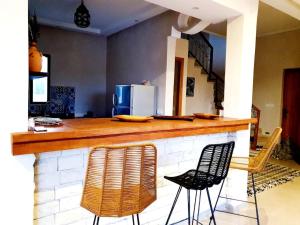 una cucina con bar con due sedie e frigorifero di Villa avec piscine privé a El Araïch