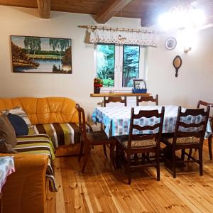 a dining room with a table and chairs and a couch at Domek letniskowy Ali in Przejma Wielka