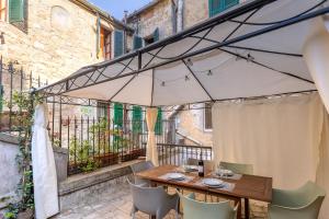 a wooden table and chairs under an umbrella on a balcony at La Corte del Podestà in Sarteano