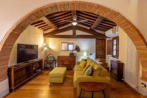 a living room with a yellow couch and a tv at La Corte del Podestà in Sarteano