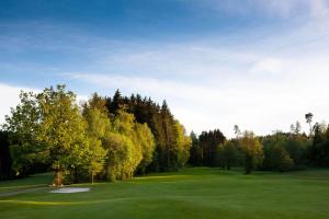 un campo de golf con árboles y un campo verde en Golfhotel Bodensee, en Weißensberg