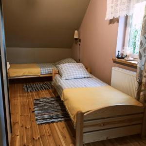 two beds in a room with wooden floors and a window at Domek letniskowy Ali in Przejma Wielka