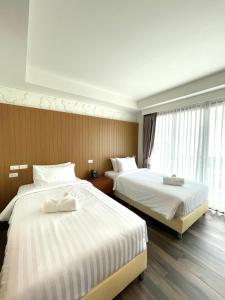 Cette chambre comprend 2 lits et une fenêtre. dans l'établissement Baannalin Hometel บ้านนลิน โฮมเทล, à Chiang Mai