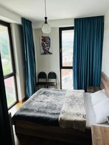 1 dormitorio con 1 cama grande y cortinas azules en BOBLINE BAKURIANI SUITE en Bakuriani