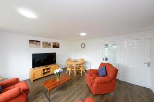 Sala de estar con 2 sillas de color naranja y TV en Premier Apt - Bridge View-Rosyth, en Rosyth