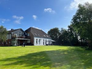 ein großes Haus mit einem großen Hof mit grünem Gras in der Unterkunft Haus Rungholt in Emmelsbüll-Horsbüll