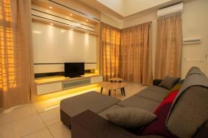 sala de estar con sofá y TV de pantalla plana en Krubong Bungalow Homestay [WiFi equipped], en Kampong Kerubong