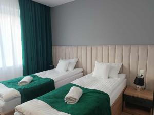 2 łóżka w pokoju zielonym i białym w obiekcie Apartamenty Centrum w Janowie Lubelskim