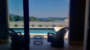 two chairs and a table on a balcony with a pool at Villa Bay View in Stari Grad